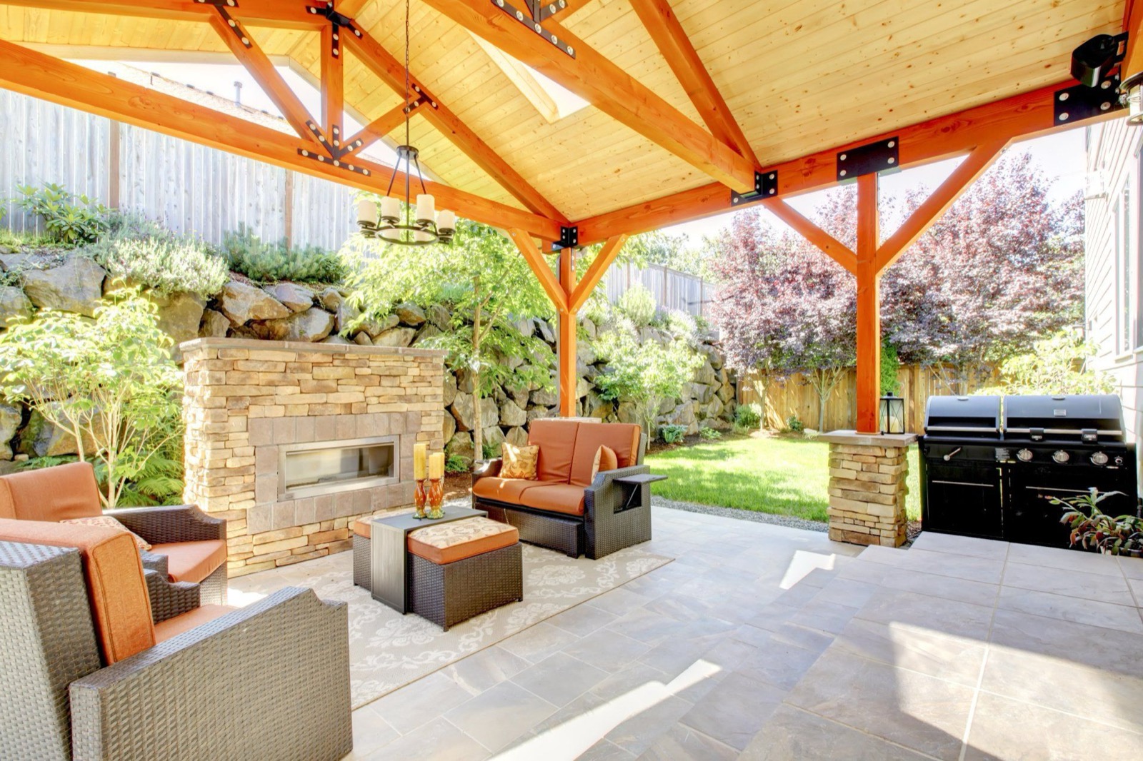 Finished covered patio with stone fireplace by Legado Outdoor Living